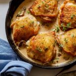 A close up of crispy chicken thighs with a creamy mushroom sauce in a skillet.