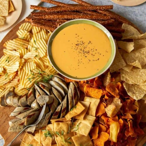 Crock pot beer cheese dip with chips and meat for dipping.