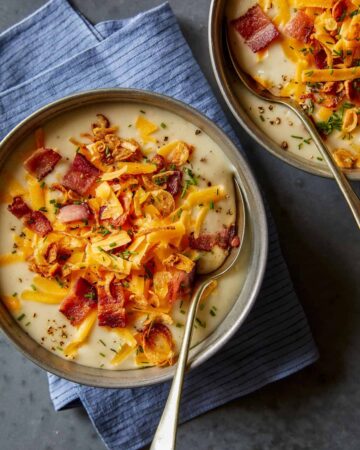 Bowls of loaded baked potato soup with spoons.