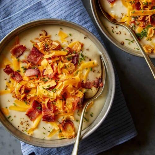 Bowls of loaded baked potato soup with spoons.