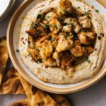 Spicy roasted cauliflower over hummus in a bowl with pita chips.