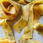 A close up of uncooked herb laced pappardelle.