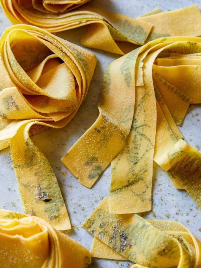 A close up of uncooked herb laced pappardelle.