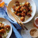 Bowls of honey garlic cauliflower over white rice with chopsticks.