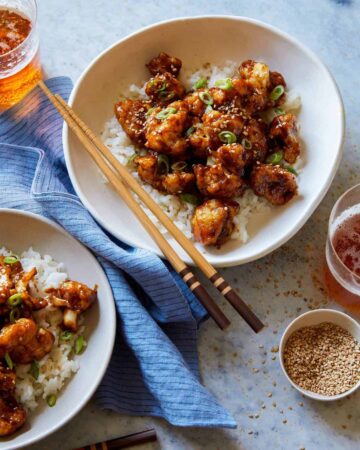 Bowls of honey garlic cauliflower over white rice with chopsticks.