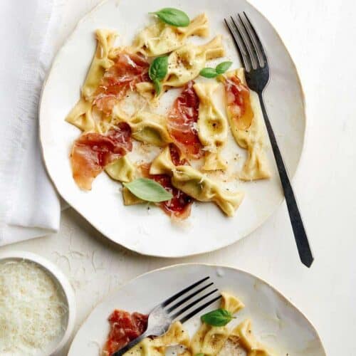 Plates of sweet pea caramelle with prosciutto and forks.