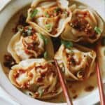 A close up of pork and shrimp dumplings with chopsticks.