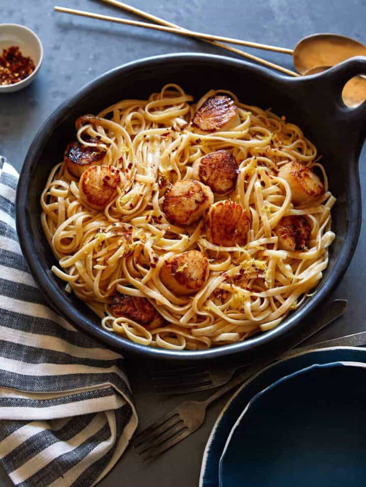 Linguine with brown butter sauce and scallops in a skillet. 