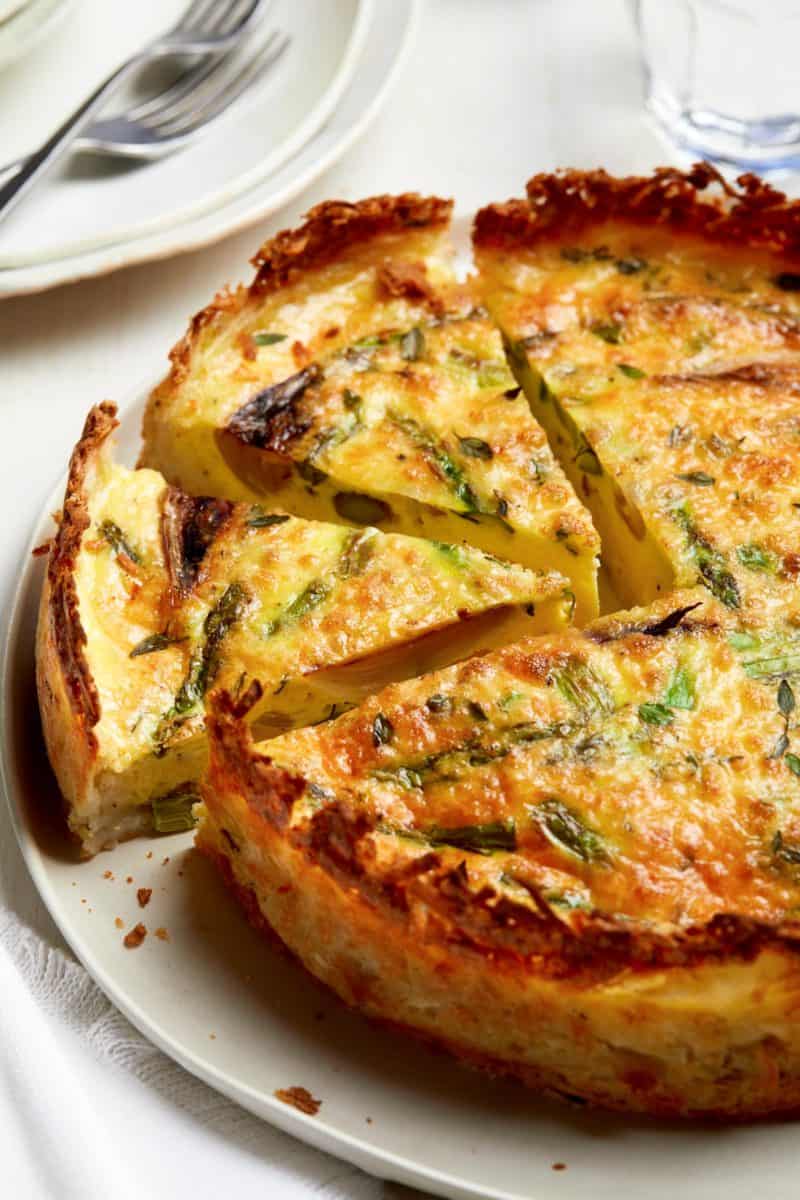 A close up of sliced spring quiche with hash brown crust.