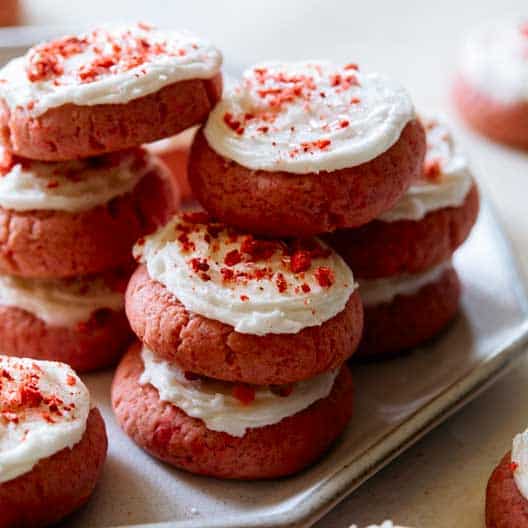 A stack of soft and fluffy strawberry cookies with vanilla frosting. 