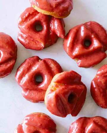 A close up of strawberry glazed old fashioned doughnuts.