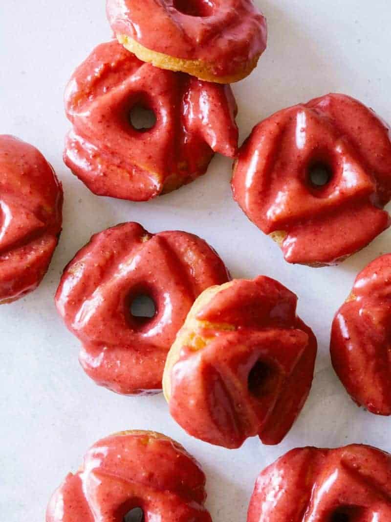 A close up of strawberry glazed old fashioned doughnuts.