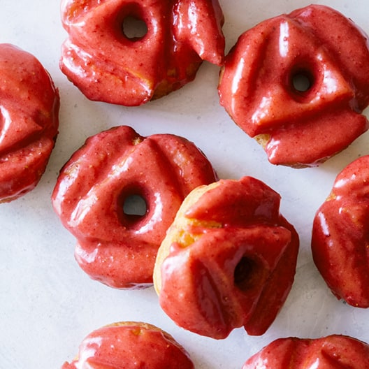 A close up of strawberry glazed old fashioned doughnuts.