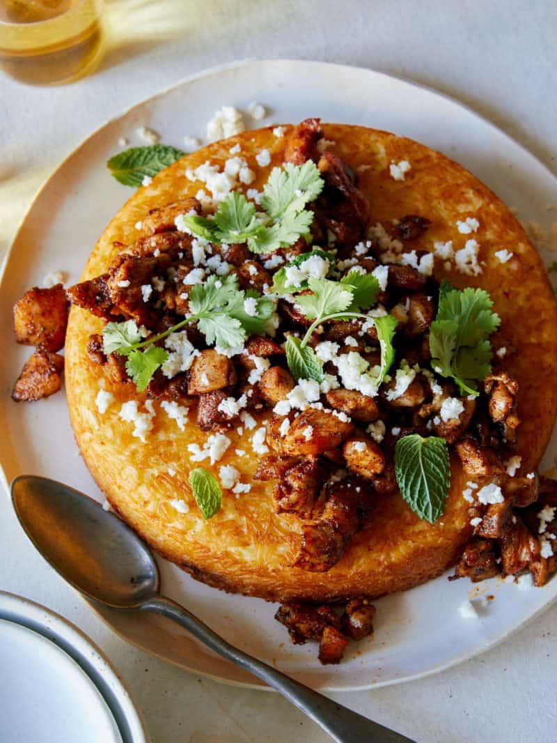 Spiced chicken topped tahchin on a plate with a spoon.