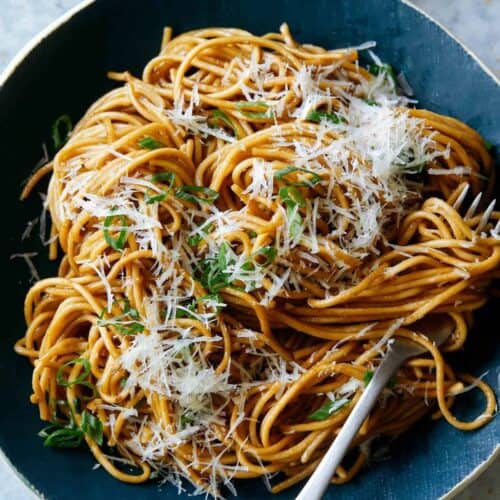 Garlic noodles garnished with cheese on a blue plate with a fork.