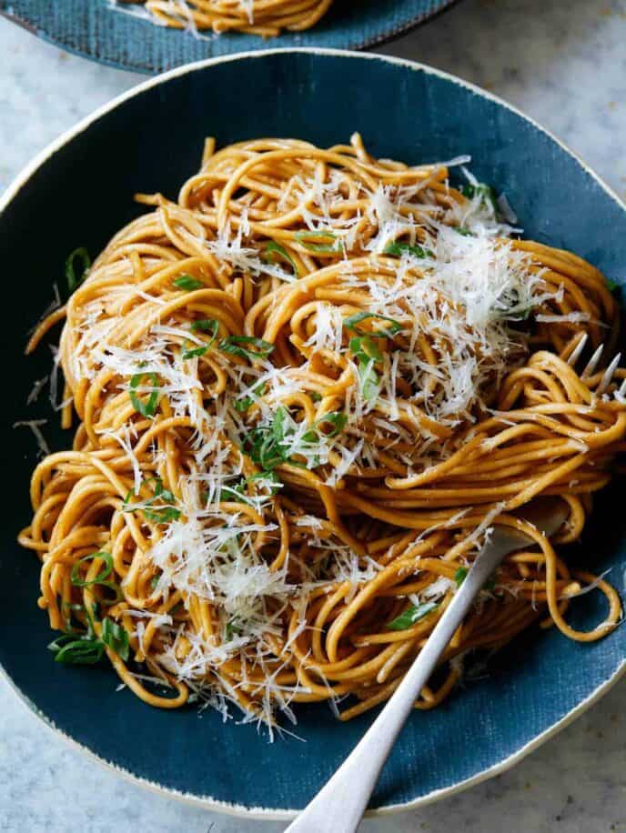 Garlic noodles garnished with cheese on a blue plate with a fork.