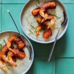 Bowls of shrimp over cheesy corn grits with spoons.