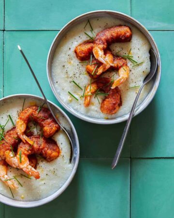 Bowls of shrimp over cheesy corn grits with spoons.