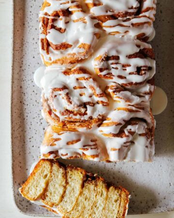A frosted cinnamon roll loaf with the end sliced off.