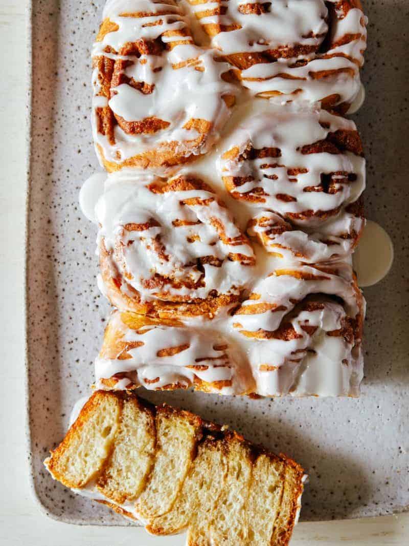 A close up of a sliced loaf of cinnamon sugar messy bread with vanilla icing.