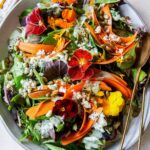 A summer salad with green goddess dressing and spoons.