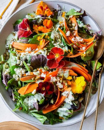 A summer salad with green goddess dressing and spoons.
