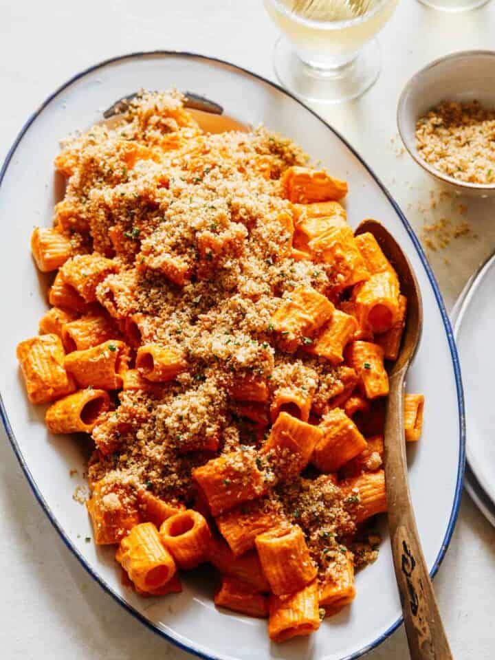 Romesco sauce rigatoni topped with breadcrumbs on a platter with a spoon.