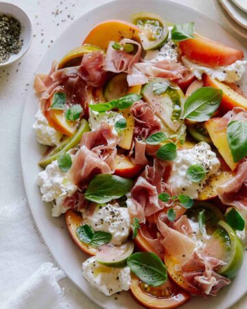 A close up of heirloom tomato, peach, and burrata summer plate.