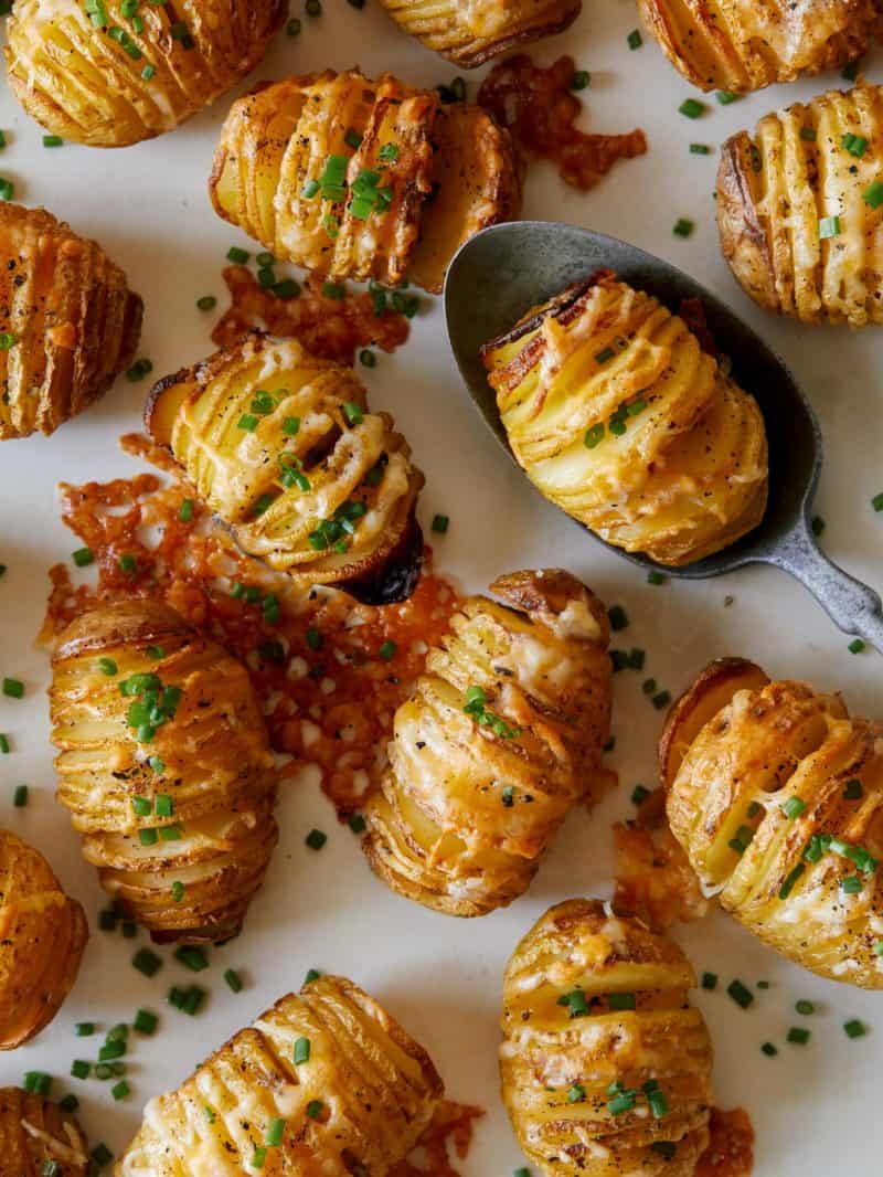 Mini cheesy hasselback potatoes with one on a spoon.