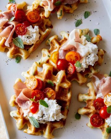 Cheesy herb waffles topped with prosciutto, burrata and tomatoes.