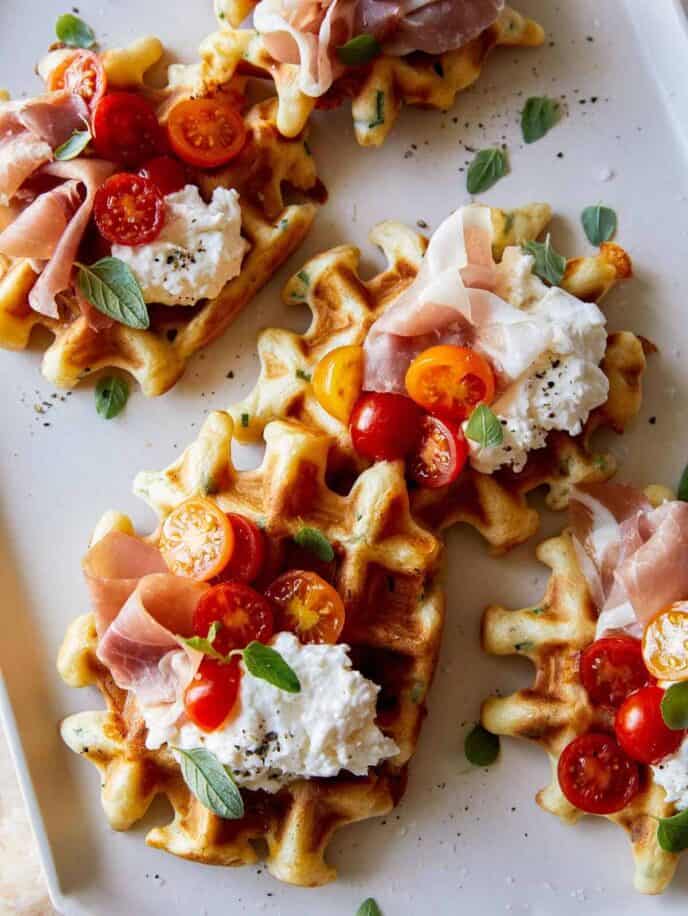Cheesy herb waffles topped with prosciutto, burrata and tomatoes.
