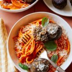 Vegan creamy roasted red pepper spaghetti and meatballs in a bowl with a fork.