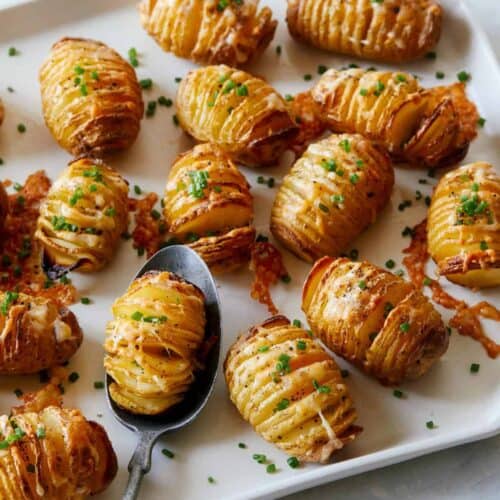 Mini cheesy hasselback potatoes with one on a spoon.