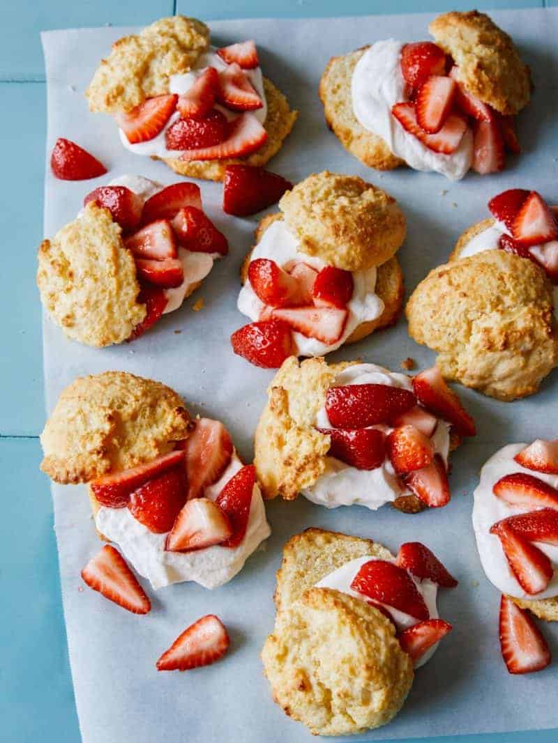 Strawberry shortcakes with cornmeal drop biscuits assembled on parchment paper.