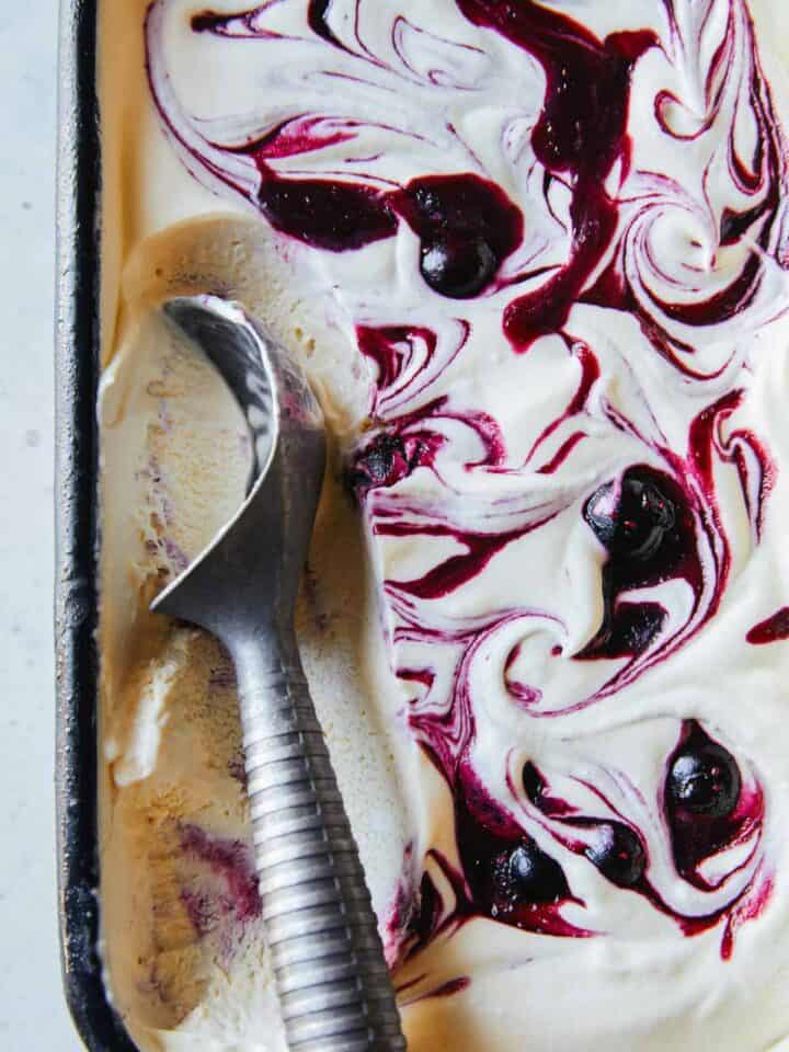 A close up of blueberry vanilla honey swirl semifreddo with ice cream scoop.