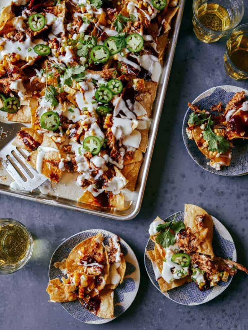 A Classic Super Bowl Snack: sheet pan of chipotle chicken nachos with servings on small plates.
