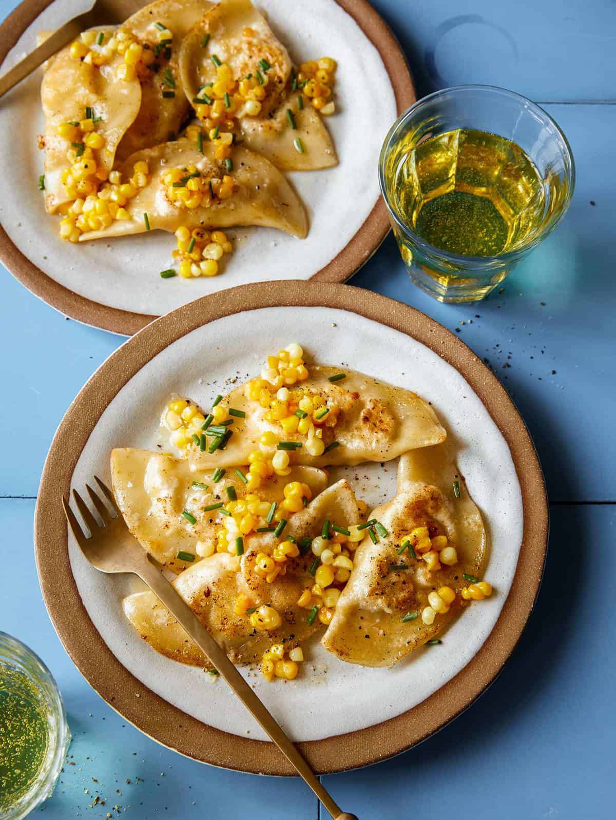 Creamy shrimp and corn ravioli on plates with a drink and fork.