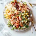 Salmon summer salad on a plate with spoons.