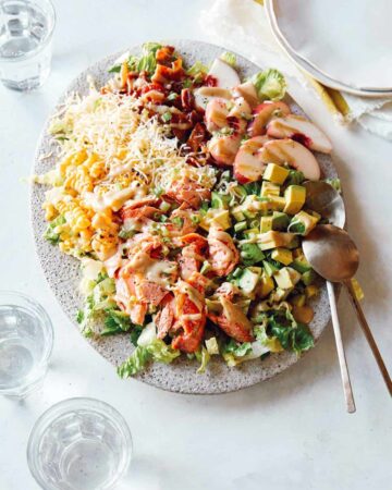 Salmon summer salad on a plate with spoons.