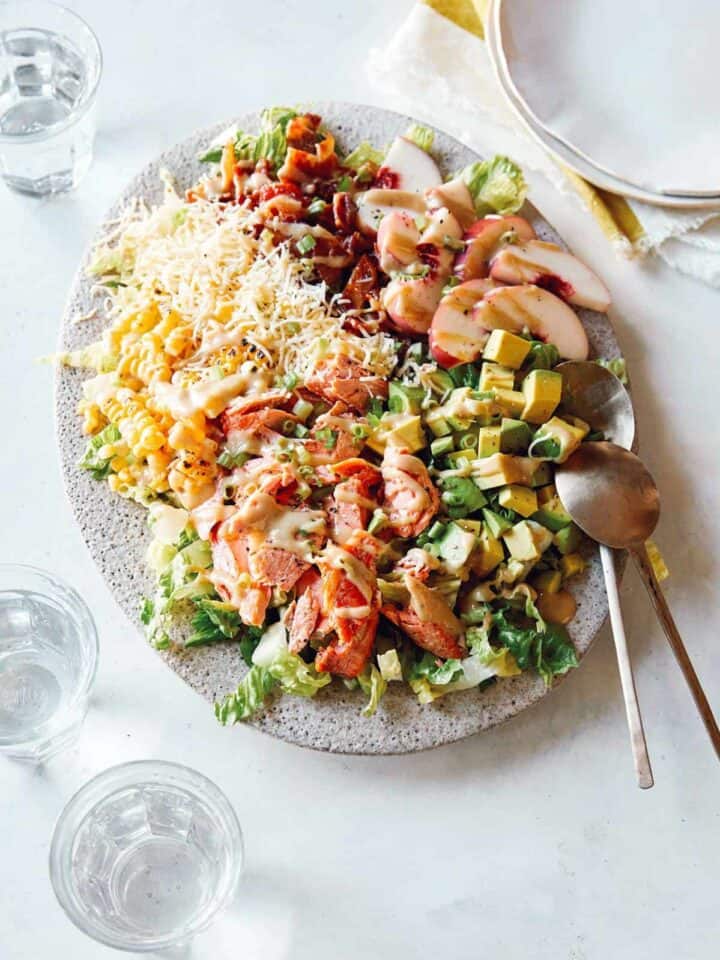 Salmon summer salad on a plate with spoons.