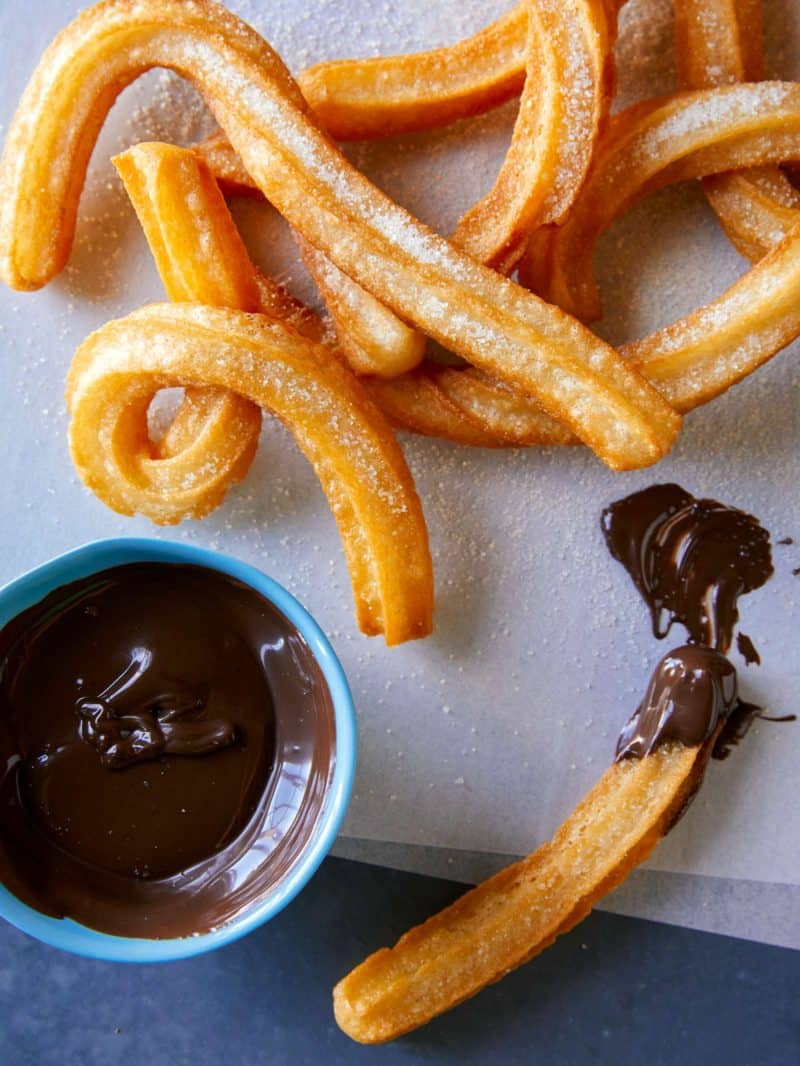 A close up of Spanish churros with a bowl of chocolate dipping sauce.