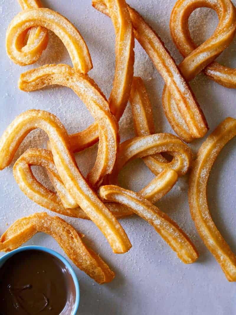 A close up of Spanish churros with a side of spicy chocolate sauce.