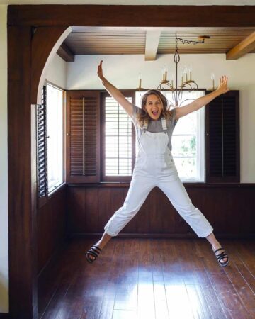 An excited woman jumping in the air with joy in an empty dining room.