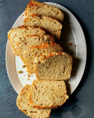 Slices of cheesy herb beer bread on a white plate.
