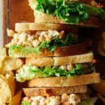 Lined up chickpea salad sandwiches with potato chips.