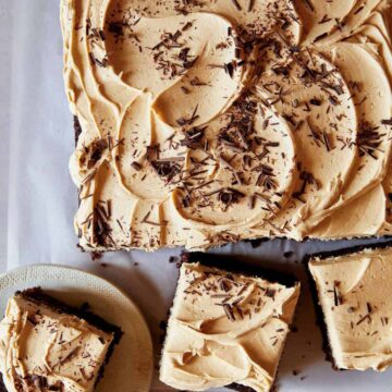 A chocolate sheet cake covered in peanut butter frosting with pieces cut off.