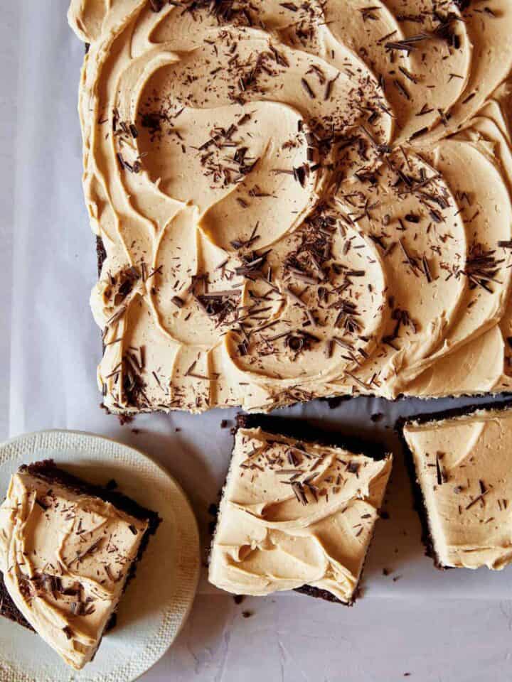 A chocolate sheet cake covered in peanut butter frosting with pieces cut off.