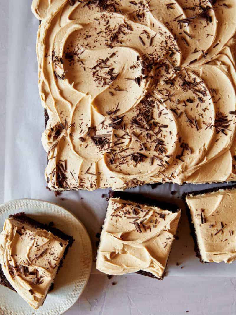 A chocolate sheet cake covered in peanut butter frosting with pieces cut off. 