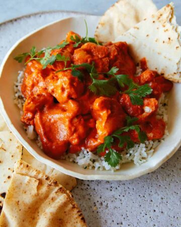 Indian butter cauliflower over white rice in a bowl with pita bread.