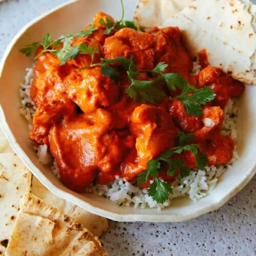 Indian butter cauliflower over white rice in a bowl with pita bread.